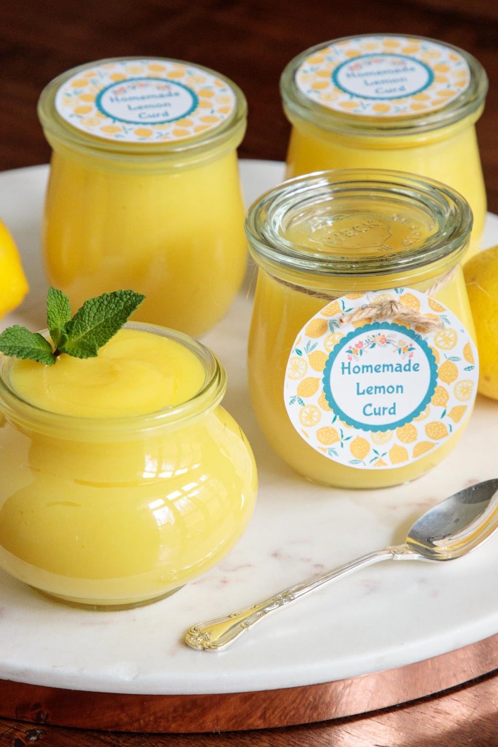 Vertical closeup photo of Weck glass jars filled with Ridiculously Easy Microwave Lemon Curd with custom gift labels.
