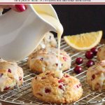 Vertical closeup photo of a batch of Ridiculously Easy Orange Cranberry Scones with one of the scones having glaze poured over it.