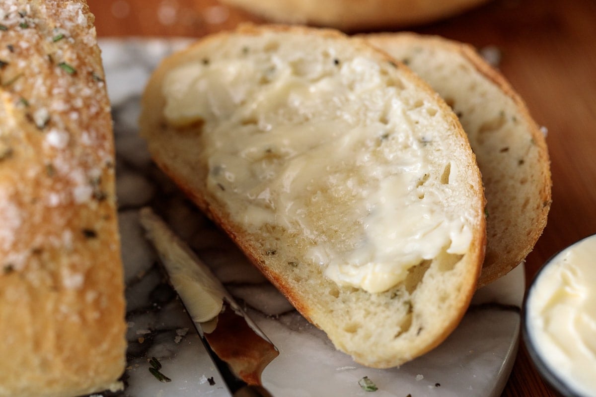 Horizontal extreme closeup photo of buttered slices of Ridiculously Easy Rosemary Bread.