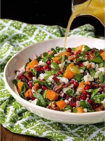 Vertical picture of Roasted Butternut Salad in a white bowl on a green and white napkin