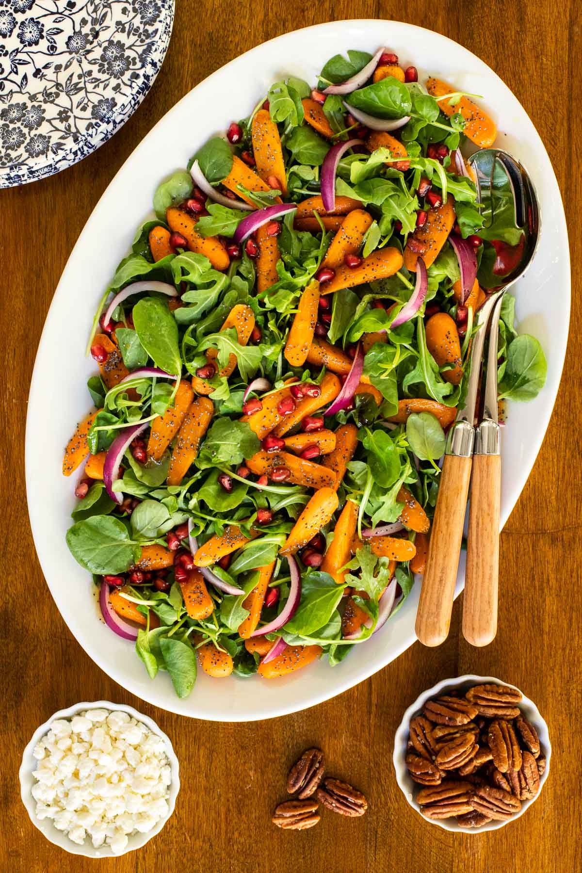 Overhead vertical photo of Roasted Carrot Salad on a white oval serving platter on a wood table.