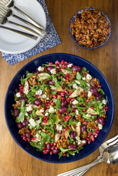 Overhead picture of Roasted Grape Arugula Salad in a blue bowl on a wooden table