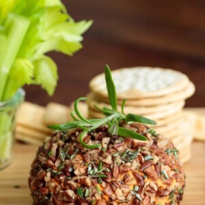 Vertical picture of roasted red pepper cheeseball on a wooden cutting board