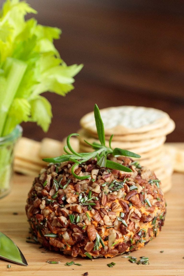 Vertical picture of roasted red pepper cheeseball on a wooden cutting board