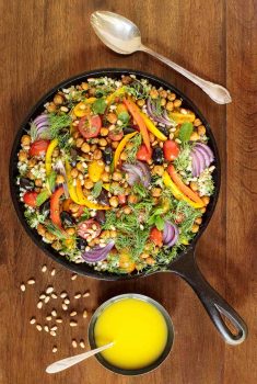 Vertical overhead photo of a skillet filled with Roasted Veggie and Crispy Chickpea Salad on a wood table.