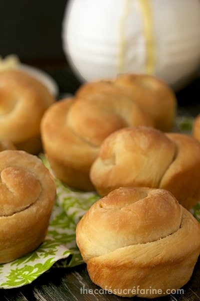 Photo of a group of Buttermilk Honey 5 Minute Dinner Rolls on a green and white napkin with a white honey jar in the background.