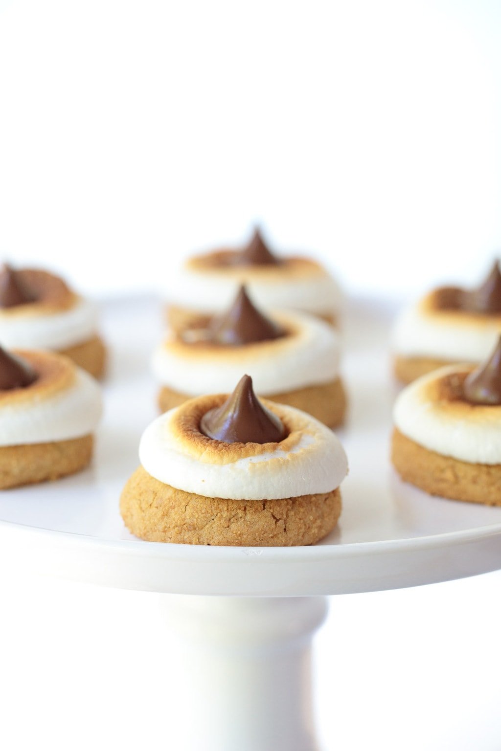 Vertical photo of S'mores Blossom Cookies on a white pedestal cake stand.