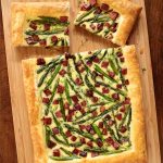 Overhead picture of savory puff pastry tart on a wooden cutting board