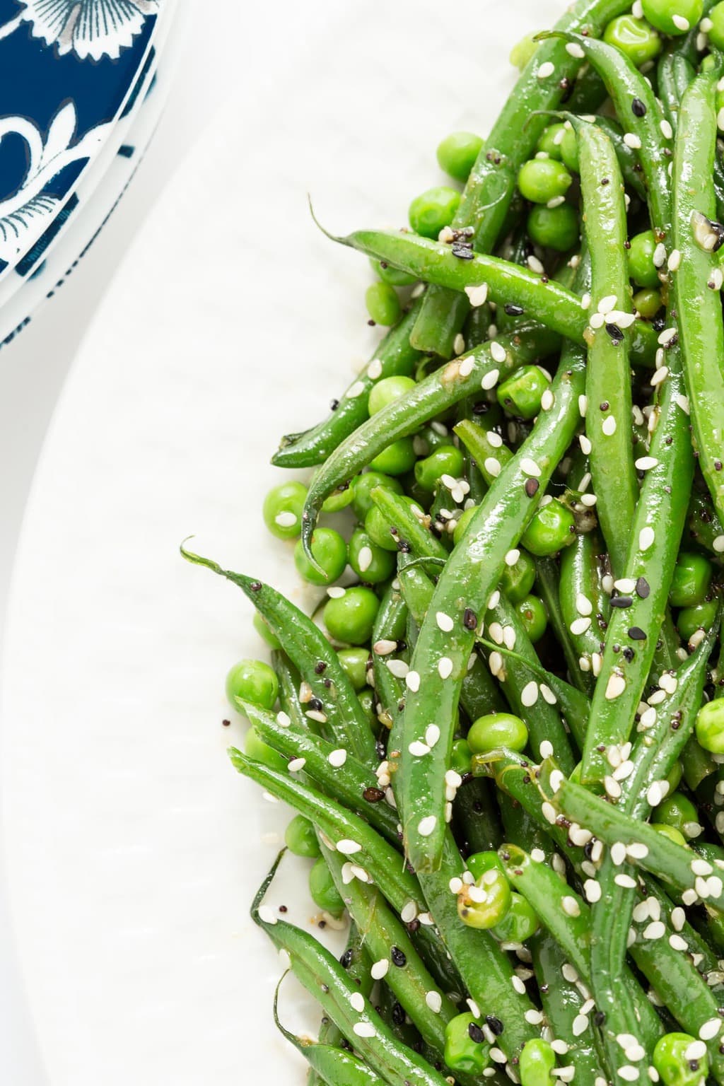Vertical extreme closeup photo of Sesame Ginger Green Bean Salad on a white serving plate.
