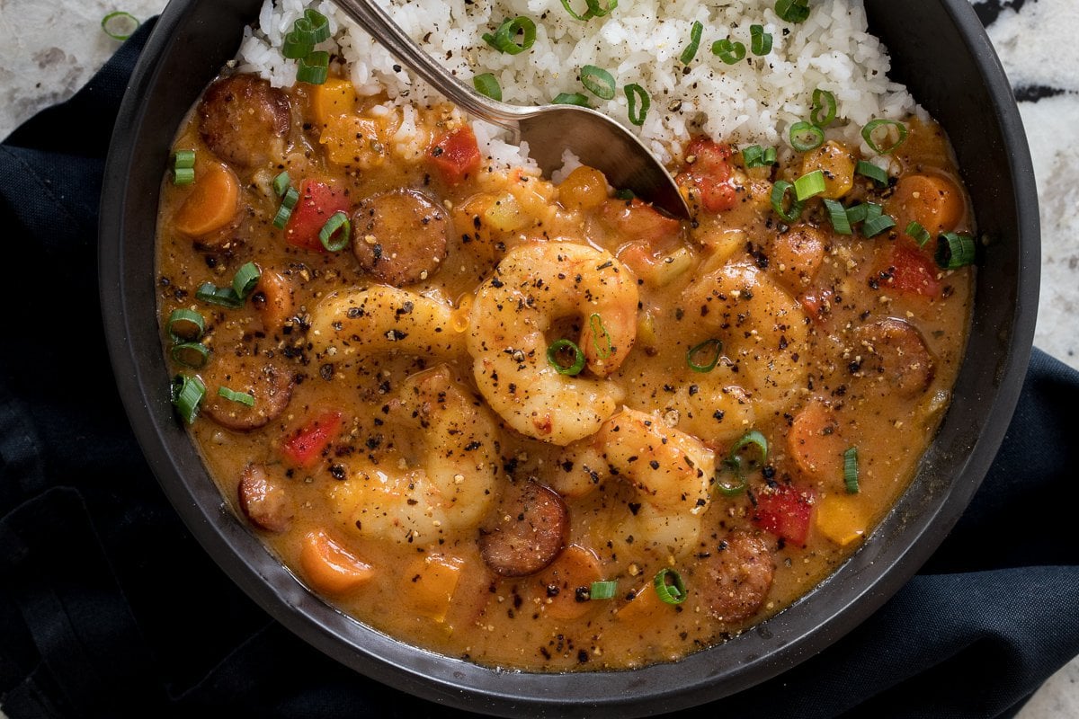 Overhead photo of a black bowl of Shrimp and Andouille Gumbo on a granite countertop with a black napkin.