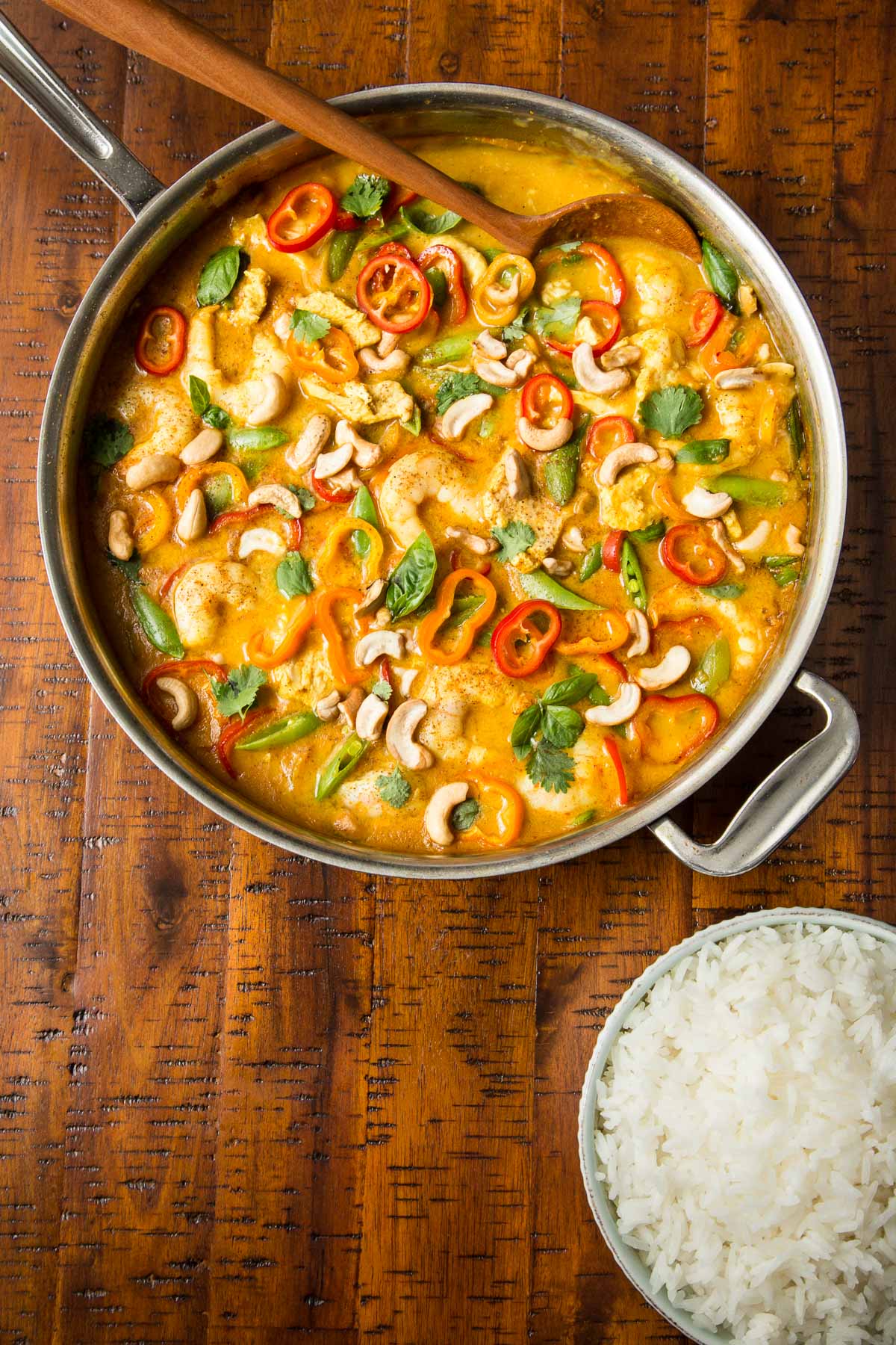 Overhead photo of a stainless steel pan filled with Shrimp and Chicken Cashew Curry on a wood table.