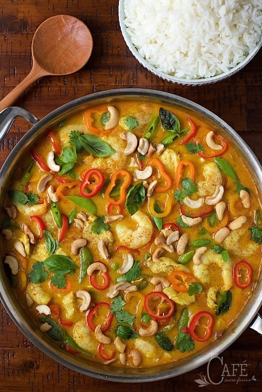 Overhead view of Shrimp and Chicken Cashew Curry on a wooden table with rice
