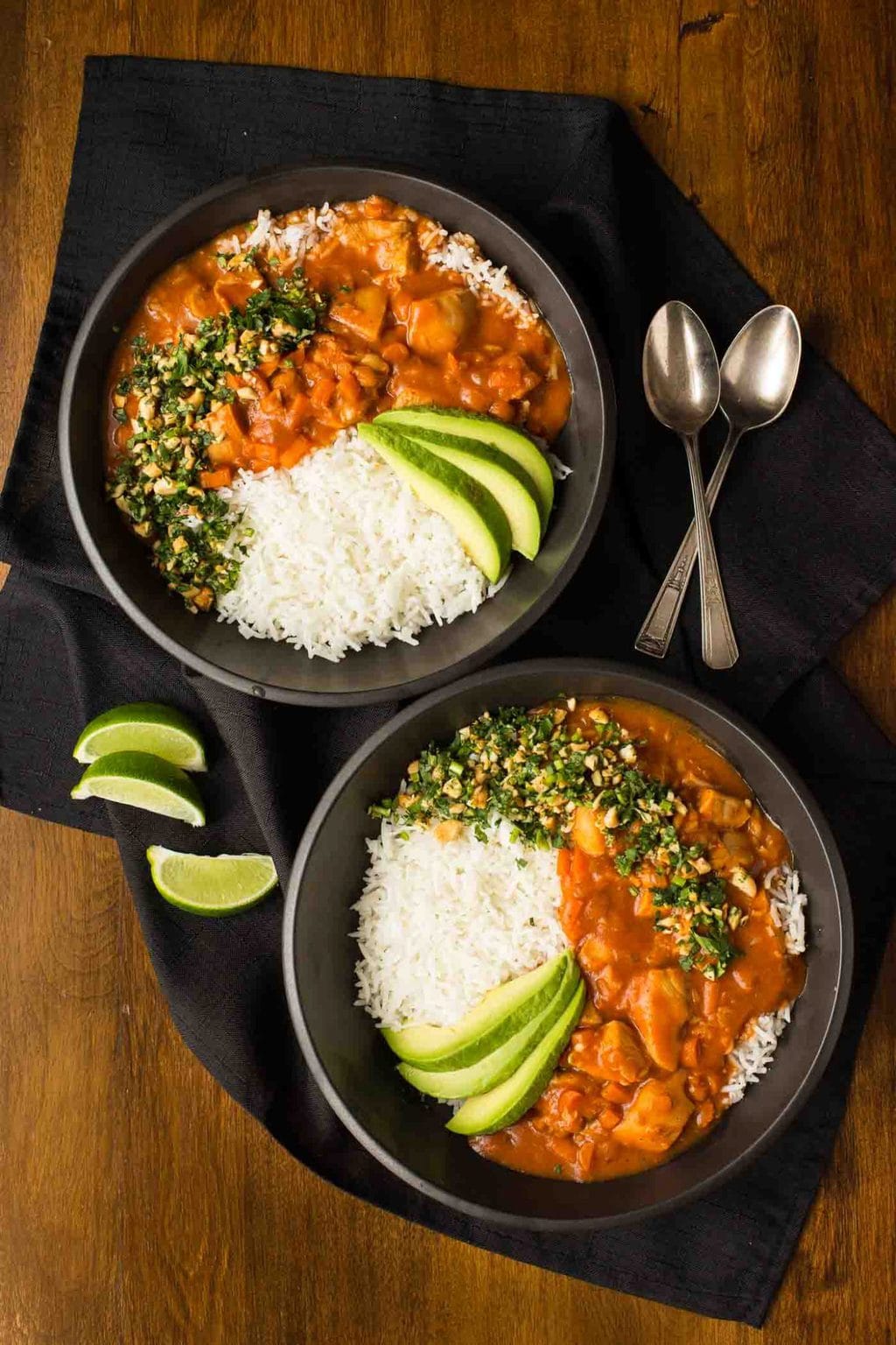 Slow Cooker Indian Butter Chicken - thecafesucrefarine.com Overhead photo of two black bowls of Slow Cooker Indian Butter Chicken with rice, cilantro cashew garnish and sliced avocados.