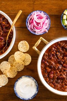 Horizontal overhead photo of Slow Roasted Short Rib Chili surrounded by garnishes and tortilla chips.