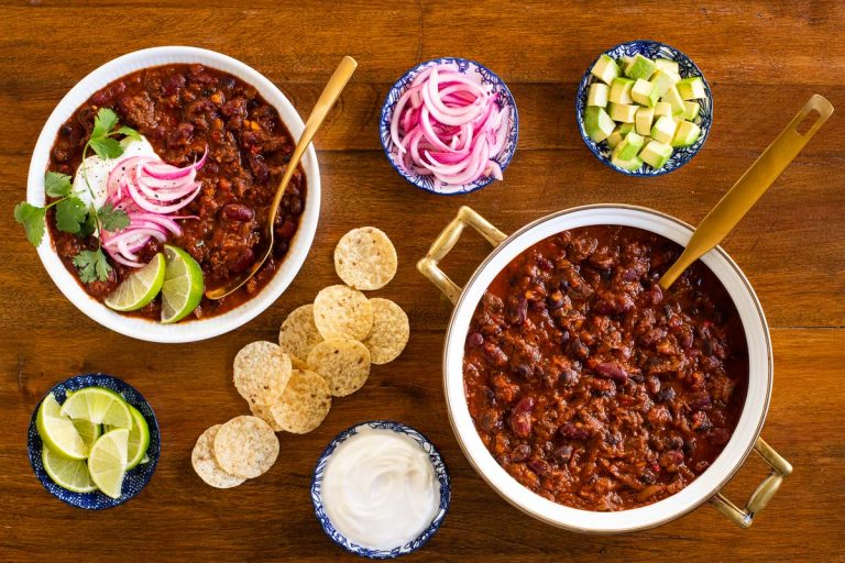 Horizontal overhead photo of Slow Roasted Short Rib Chili surrounded by garnishes and tortilla chips.