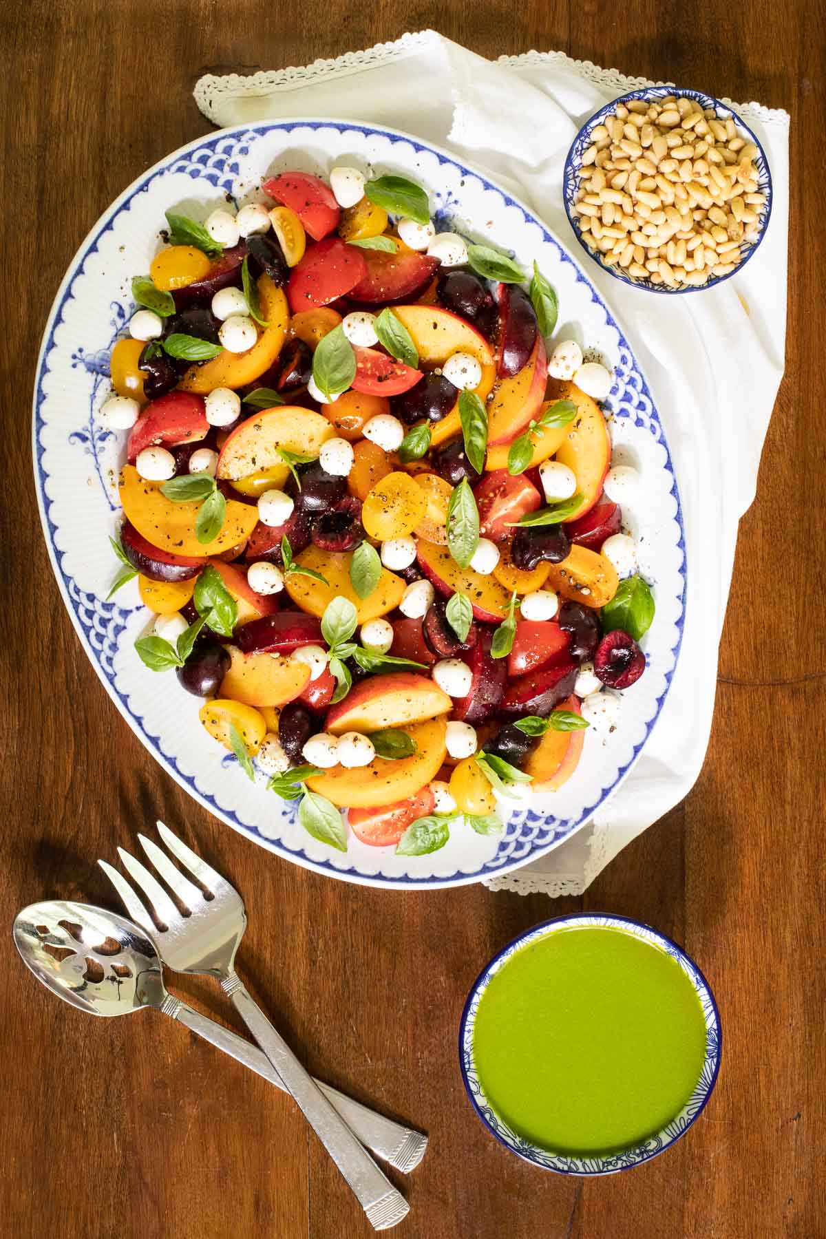 Overhead vertical photo of a Stone Fruit Tomato Salad on a white and blue patterned platter.