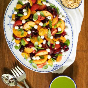 Vertical overhead picture of Stonefruit Tomato Caprese Salad on a blue and white oval platter