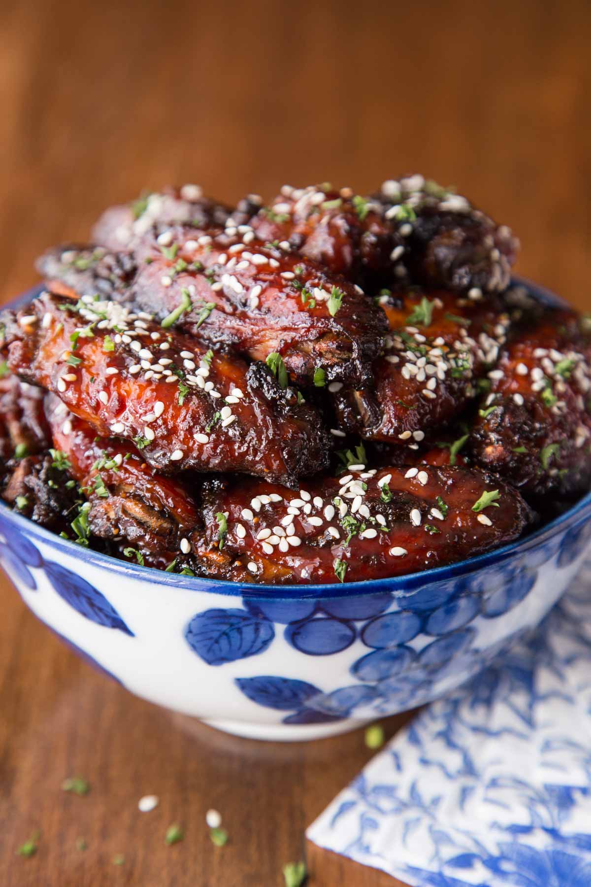 Vertical picture of strawberry balsamic chicken wings in a blue and white bowl