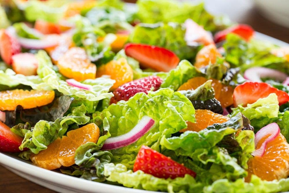 Horizontal closeup photo of a Strawberry Clementine Salad with Red Wine Vinegar Dressing on a white platter.