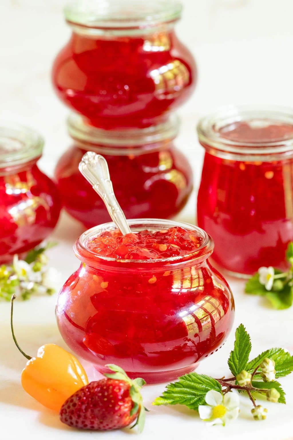 Vertical photo of Strawberry Habanero Pepper Jelly in small glass Weck jars.