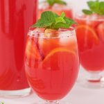Vertical picture of Strawberry Lemonade in glasses with a pitcher in the background