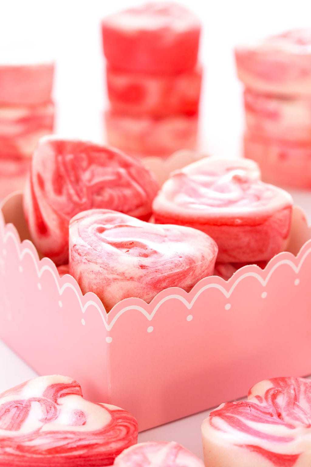 Vertical closeup photo of heart shaped Strawberry Swirled Fantasy Fudge in a pink and white gift box.