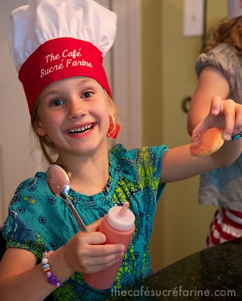 Annie presenting a glazed Strawberry Glazed Butter Thin cookie.