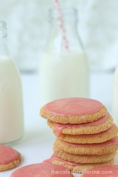 Photo of a stack of Strawberry Glazed Butter Thin cookies with mini jars of fresh milk in the background.