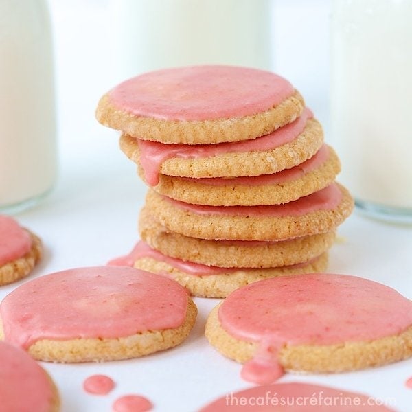 Photo of a stack of Strawberry Glazed Butter Thins with jars of milk in the background and cookies in the foreground.