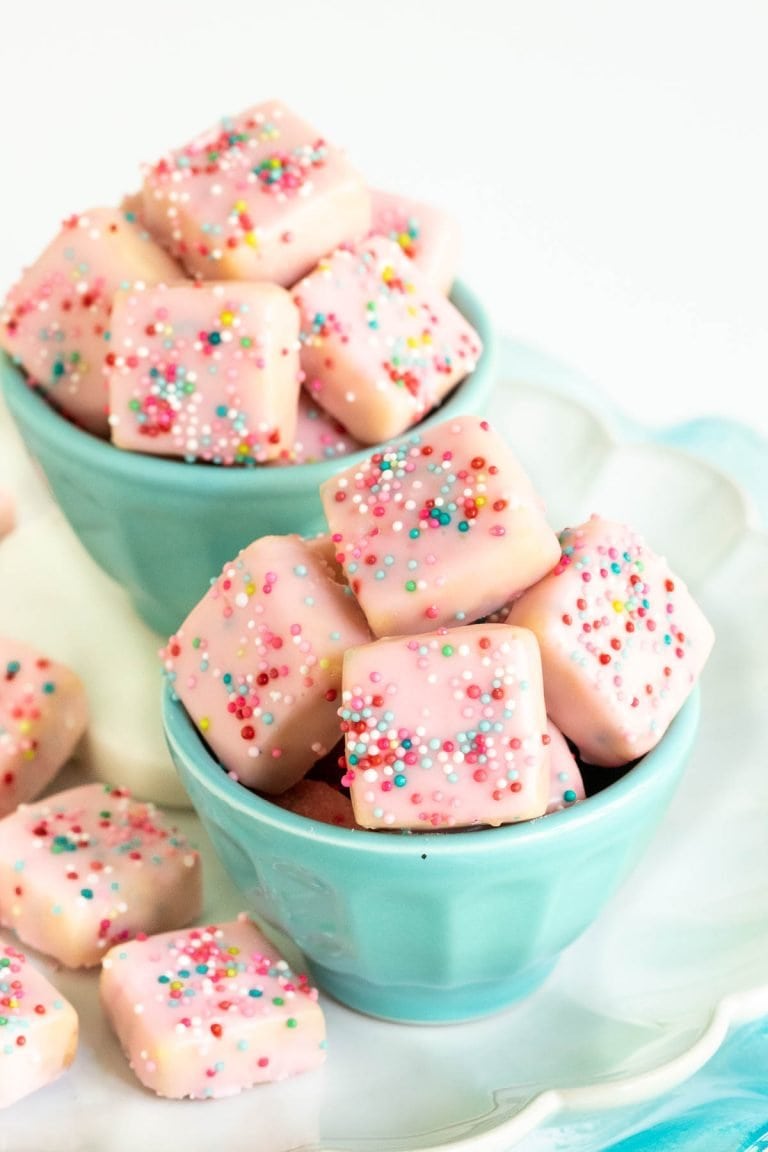 Vertical photo of two turquoise cups filled with Sugar Plum Fairy Shortbread Bites.