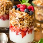 Vertical closeup photo of a glass jar of Double Almond Paleo Granola on a wood table.