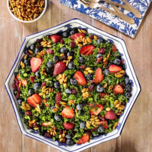 Overhead picture of summer kale salad on a wooden table with a blue and white napkin