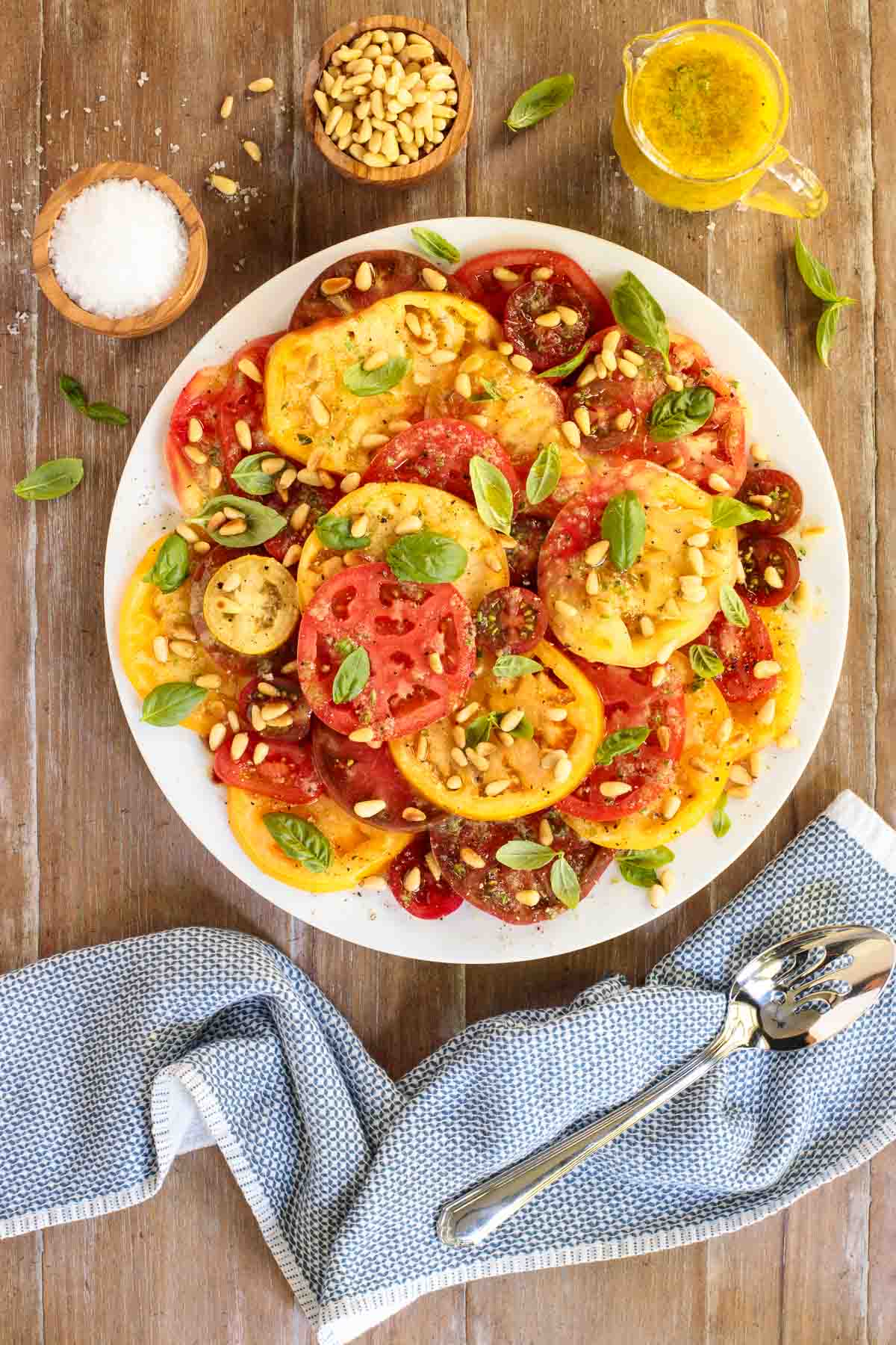Overhead picture of summer tomato salad with red and yellow tomatoes on a white plate