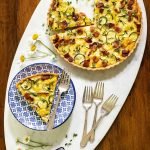 Vertical overhead photo of an Easy Zucchini Summer Quiche on an oval marble serving surface.