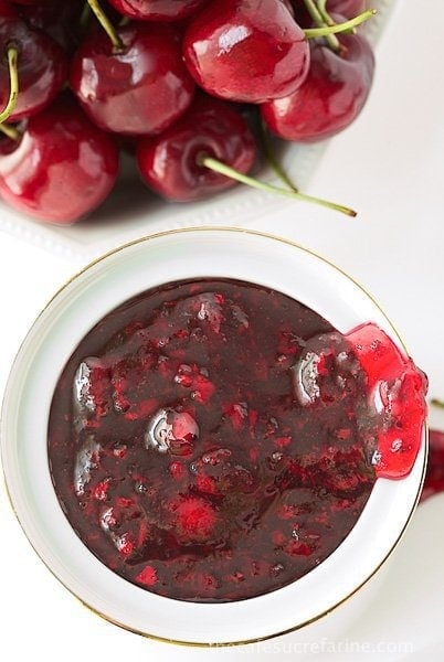 Overhead vertical photo of Sweet Cherry Freezer Jam in a white dish next to fresh cherries.