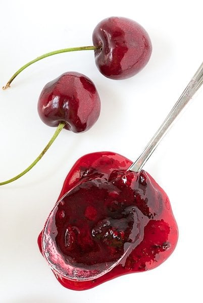 Overhead photo of fresh cherries next to a spoonful of Sweet Cherry Freezer Jam.