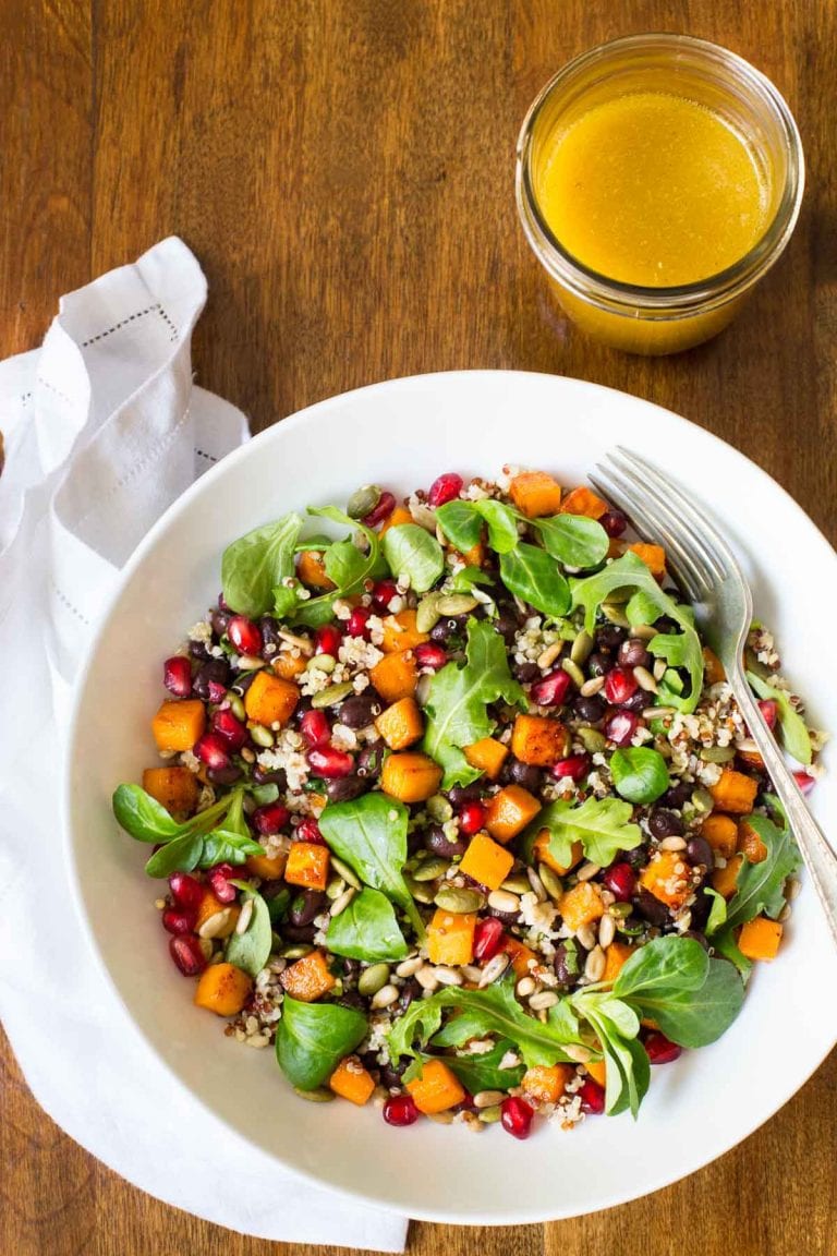 Vertical overhead picture of Sweet Potato Quinoa Salad in a white bowl with a jar of dressing