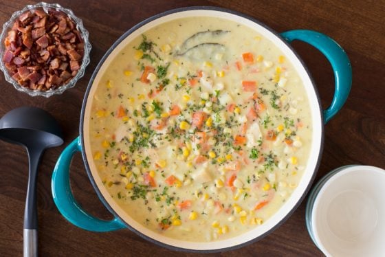 Turkey Corn Chowder in a blue dutch oven with a small bowl of bacon.