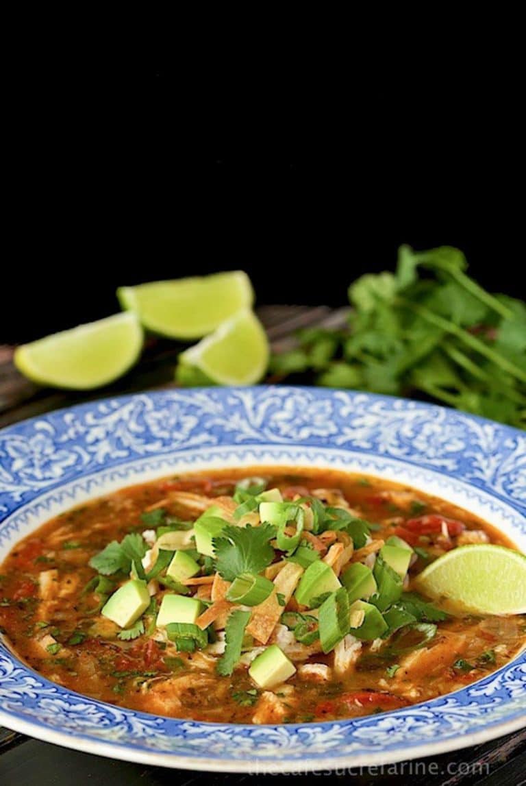 Vertical picture of turkey tortilla soup in a blue and white bowl on a black background