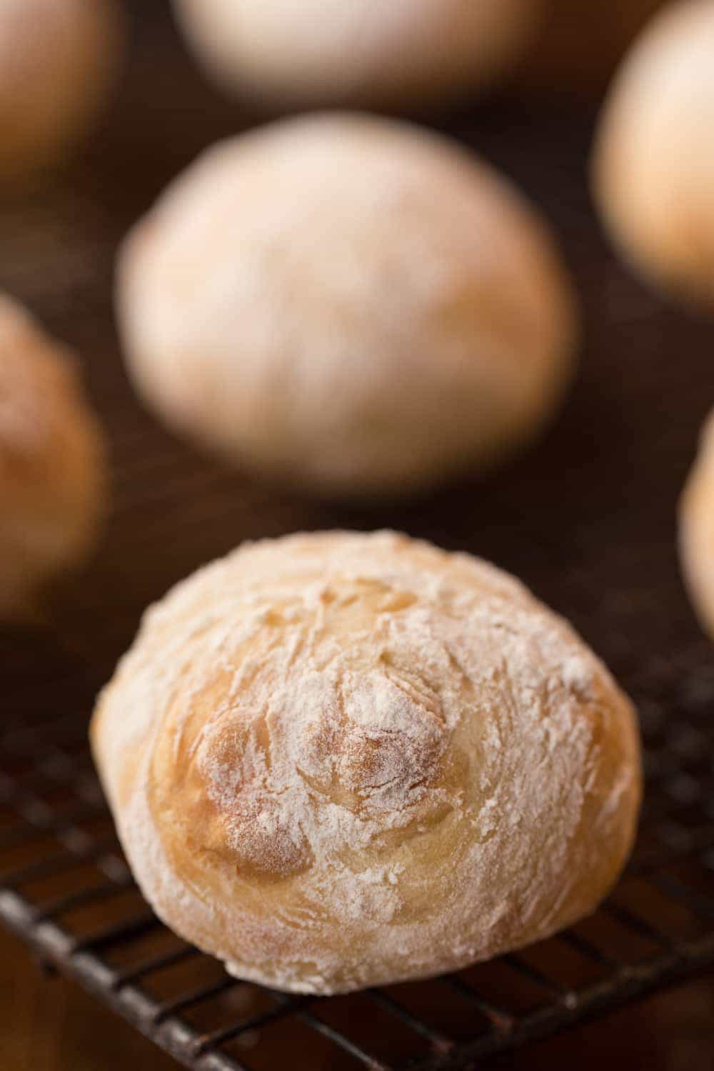 Close up vertical photo of Easy Artisan Rolls on a black metal cooling rack.