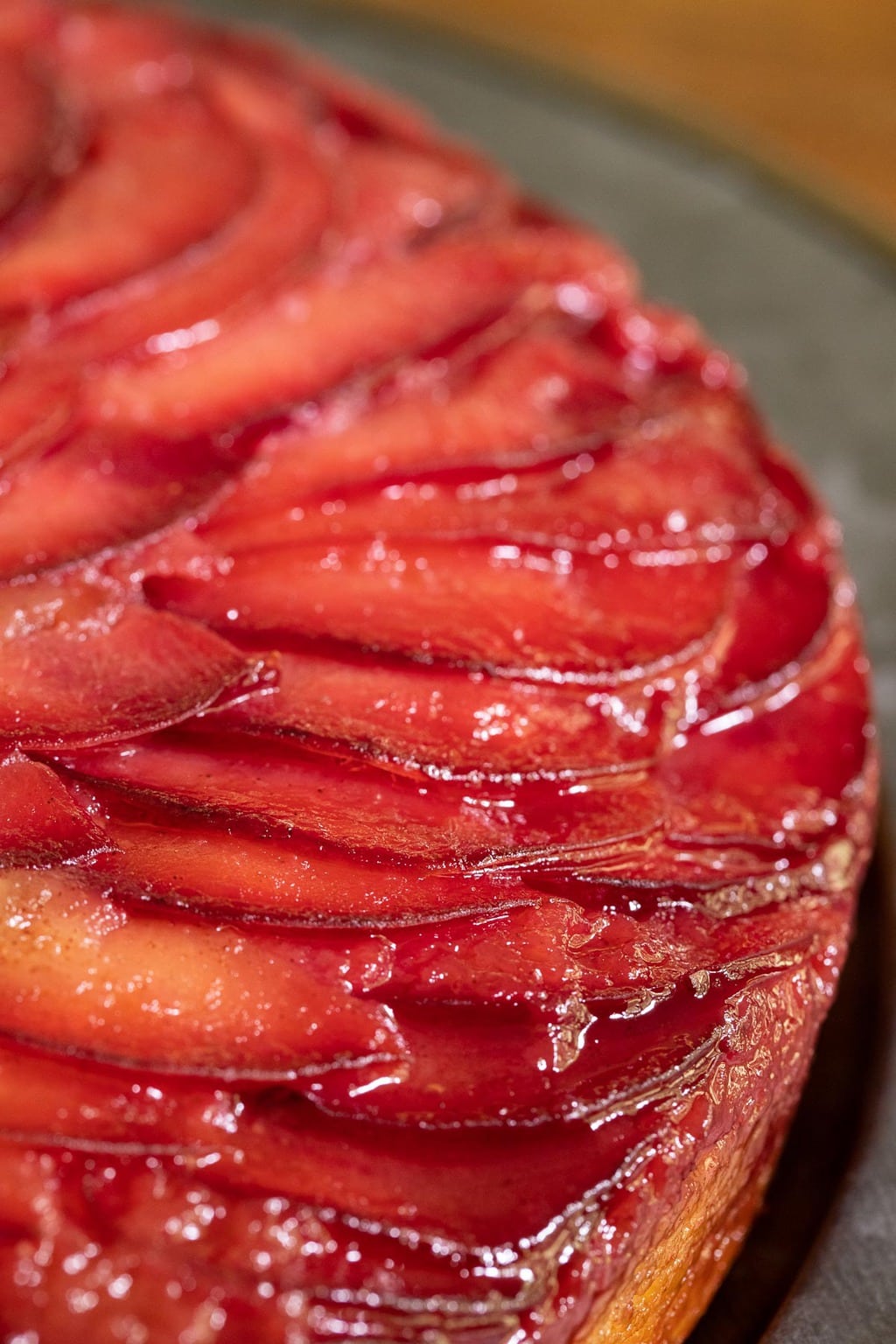 Ultra closeup vertical photo of a Upside Down Plum Cake on a steel charger plate.