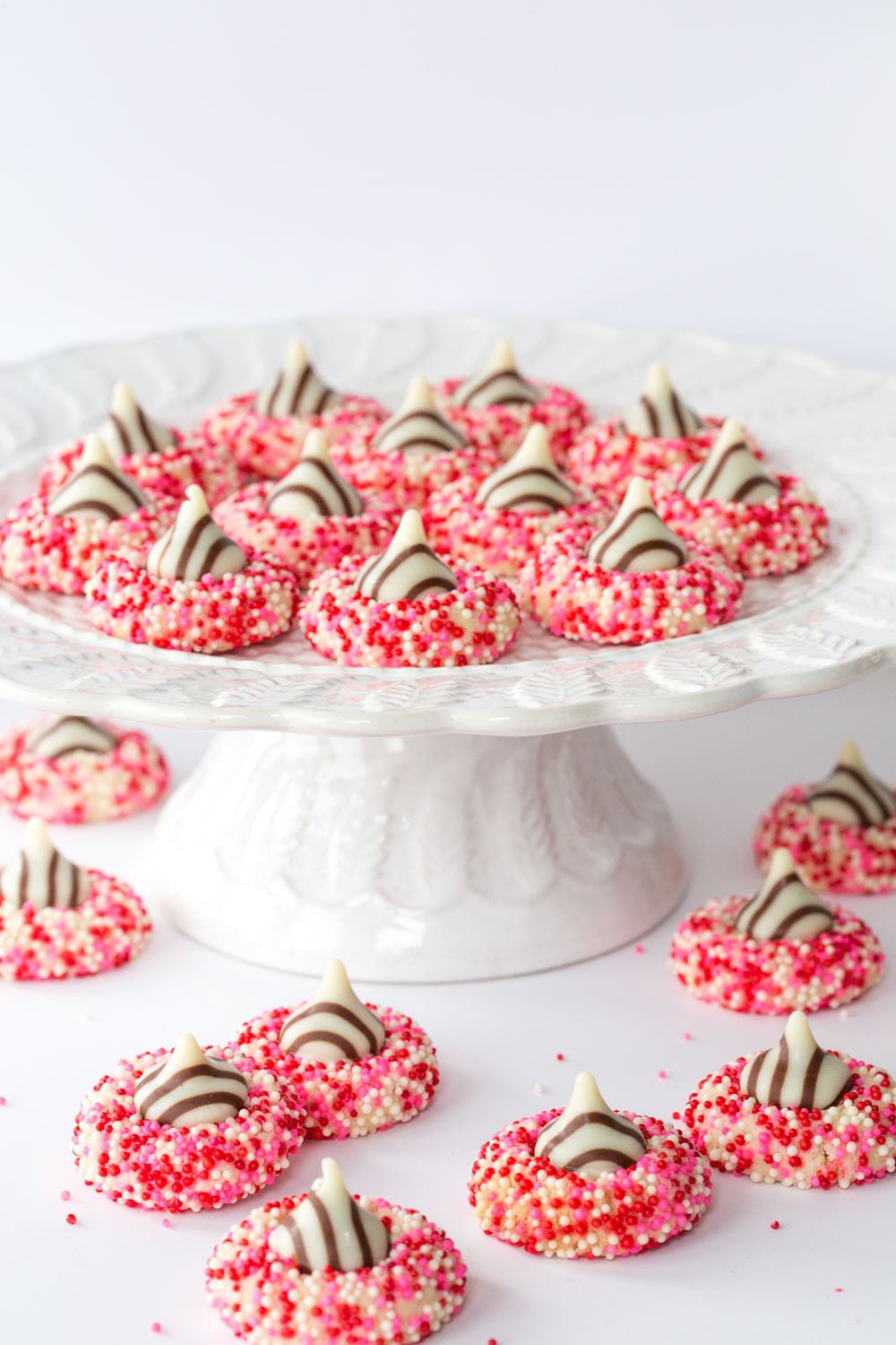 Vertical photo of Valentine Shortbread Cookies with sprinkles on a white pedestal cake stand