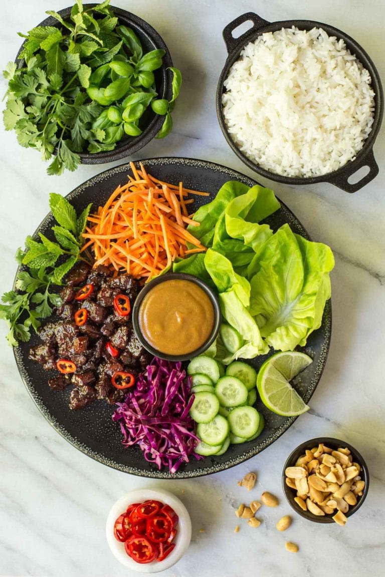 Overhead picture of Vietnamese Carmel Pork Lettuce wraps with toppings and rice on a marble table