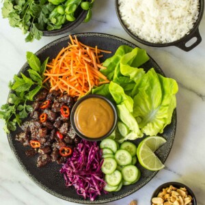 Overhead picture of Vietnamese Carmel Pork Lettuce wraps on a platter with fresh toppings
