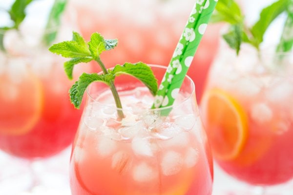 Horizontal photo of glasses of Watermelon Mint Lemonade with green straws and a sprig of mint in each glass.