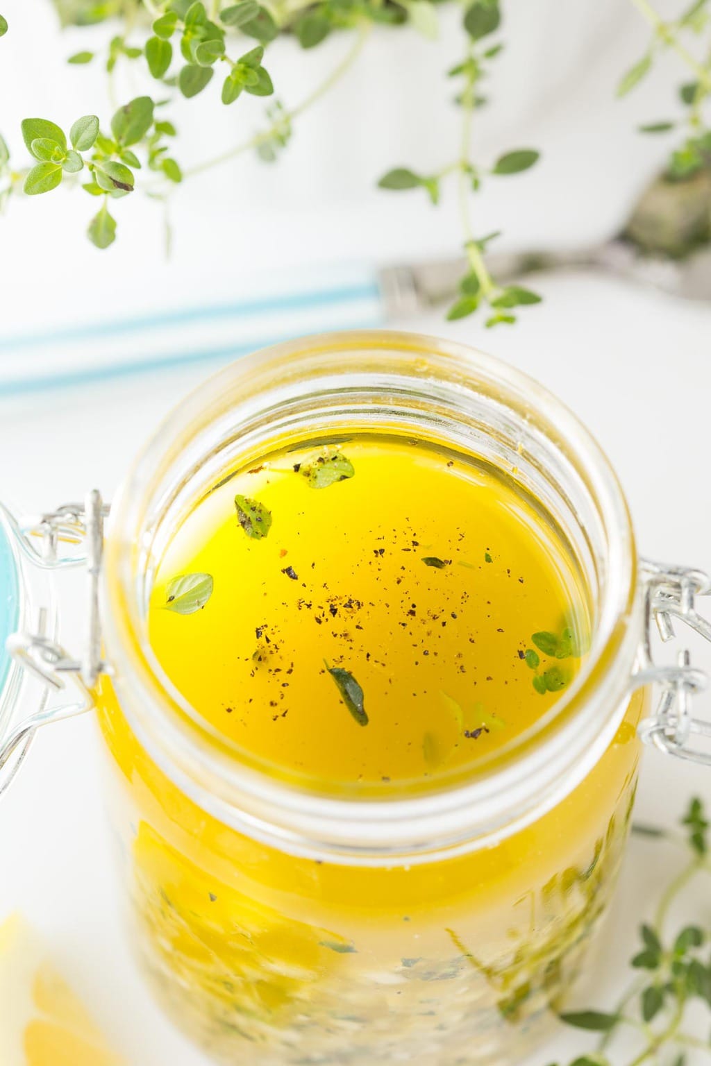 Overhead closeup photo of a jar of Whole Lemon Thyme Salad Dressing with garnishes of thyme surrounding the jar.