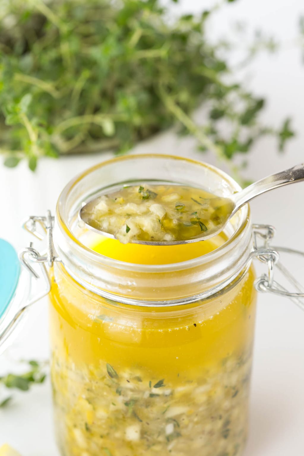 Photo of a jar of Whole Lemon Thyme Salad Dressing with a spoonful of the dressing resting on top of the jar.