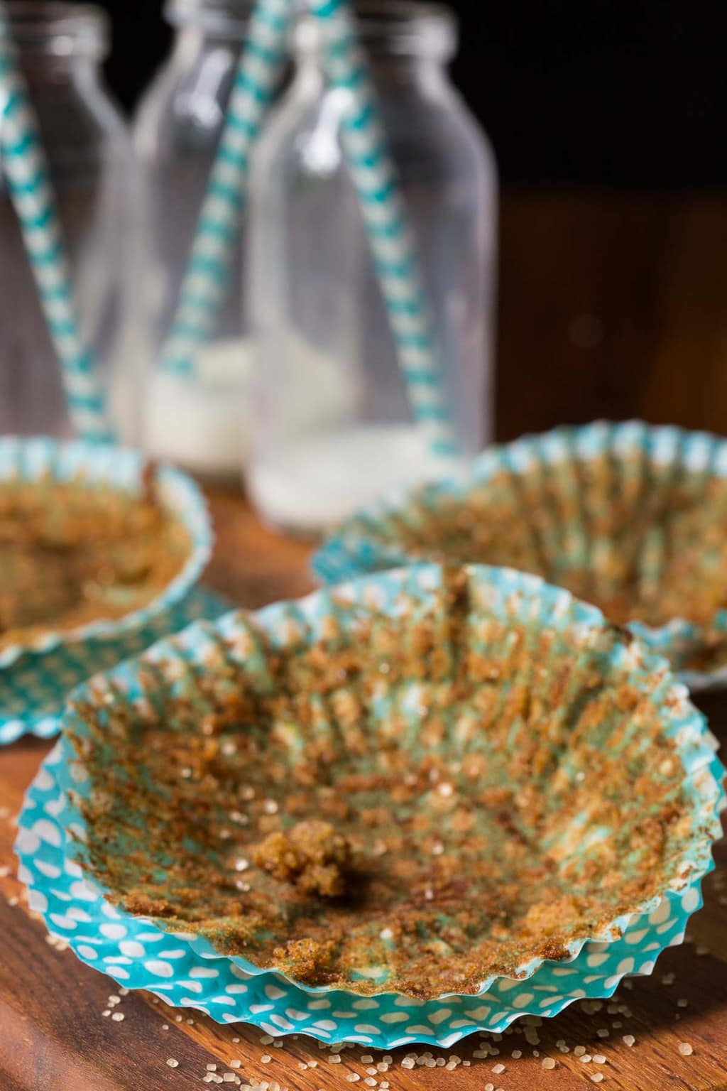 Photo of empty turquoise cupcake liners which once held Zucchini Morning Glory Muffins. Empty milk jars are in the background.