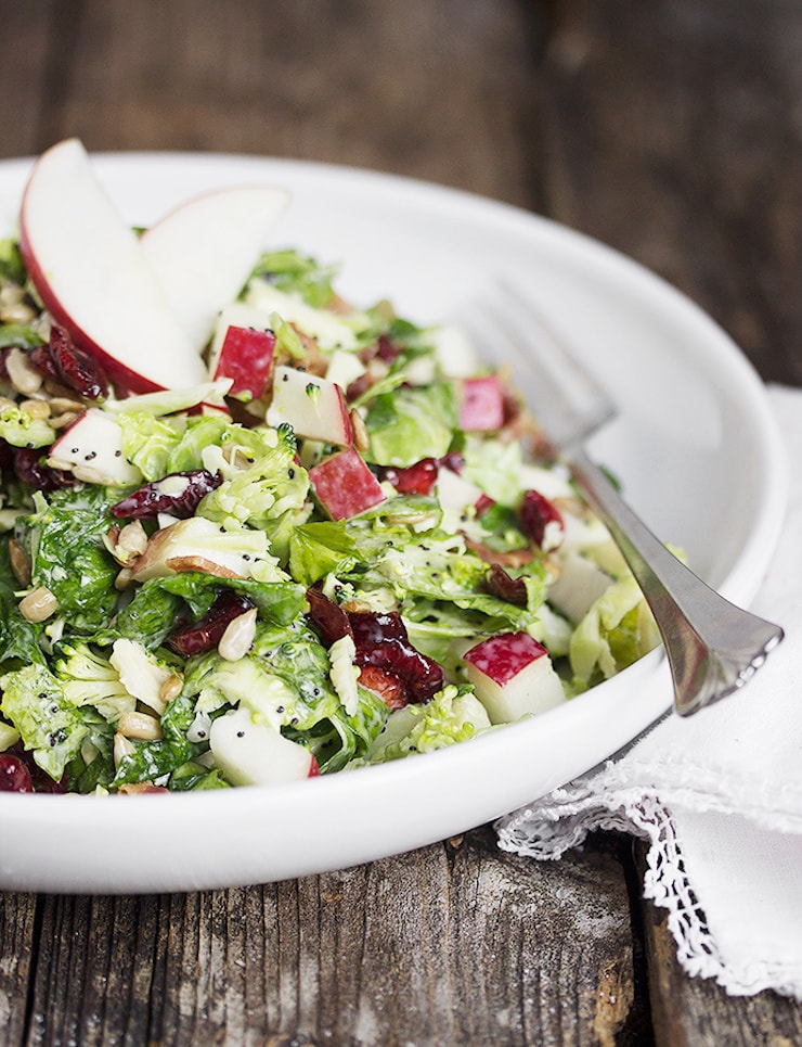 One of 15 Delicious Fall Salads - Photo of a white dish of Fall Kale Salad on a distressed wood table.