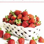 Vertical photo of a white lattice basket filled with fresh strawberries to overflowing.